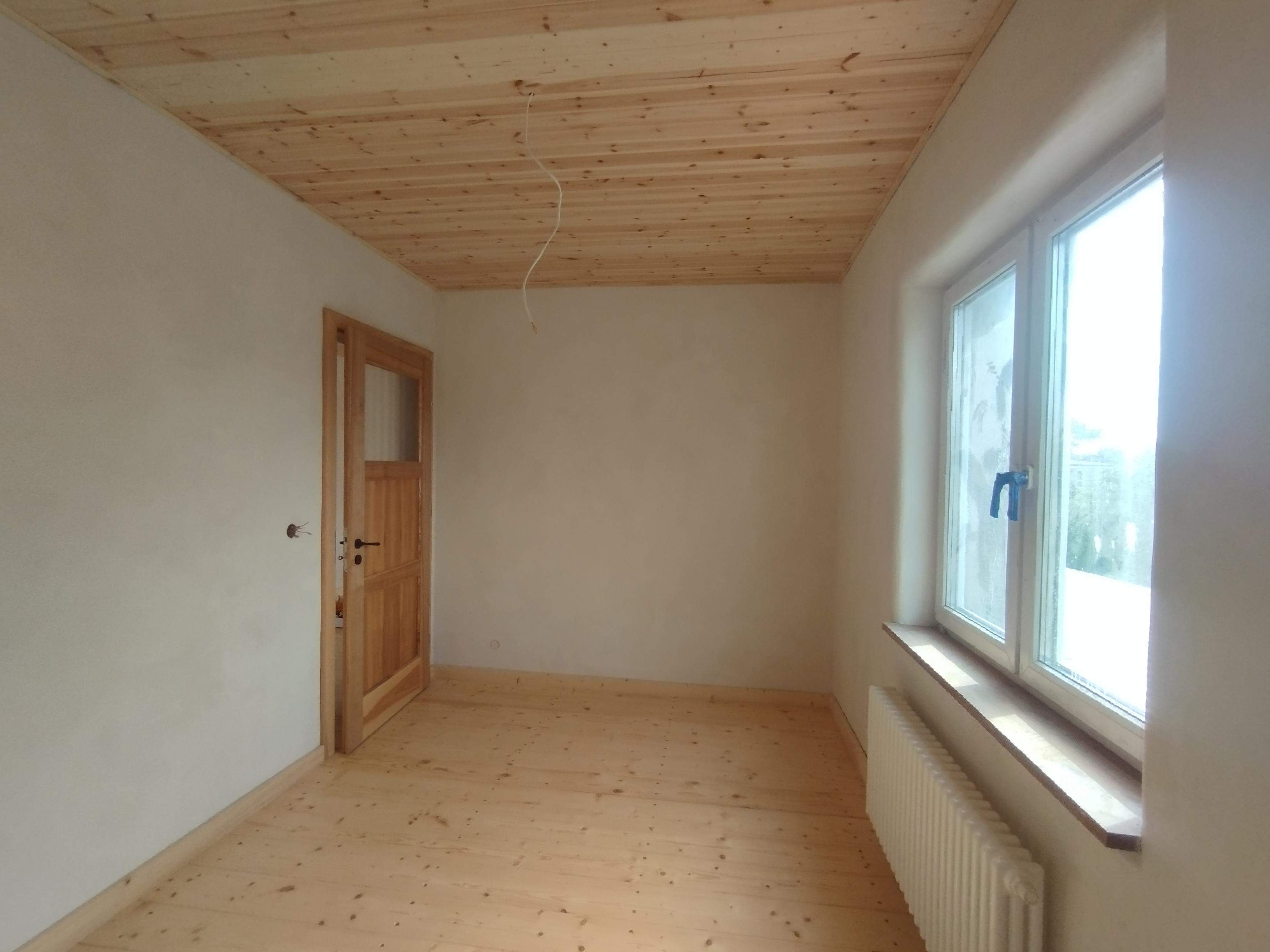 pokój z tynkiem naturalnym i drewnianą podłogą